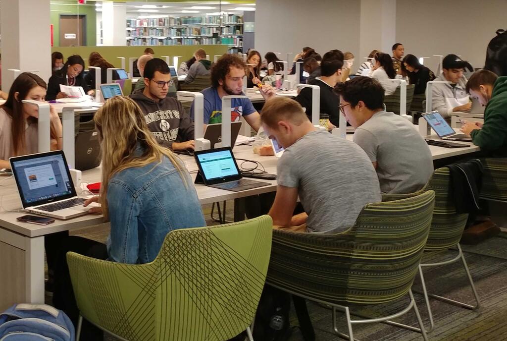 An image of students seated in the library using laptops